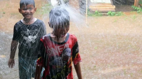 Boys are having fun playing in the rain in the yard. Stock Footage 308962893