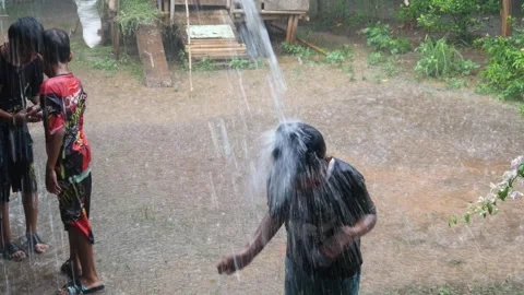 Boys are having fun playing in the rain in the yard. Stock Footage 308962894