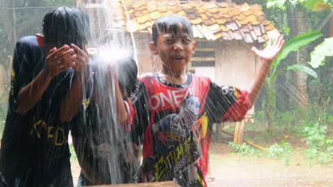 Boys are having fun playing in the rain in the yard. Stock Footage 308962898