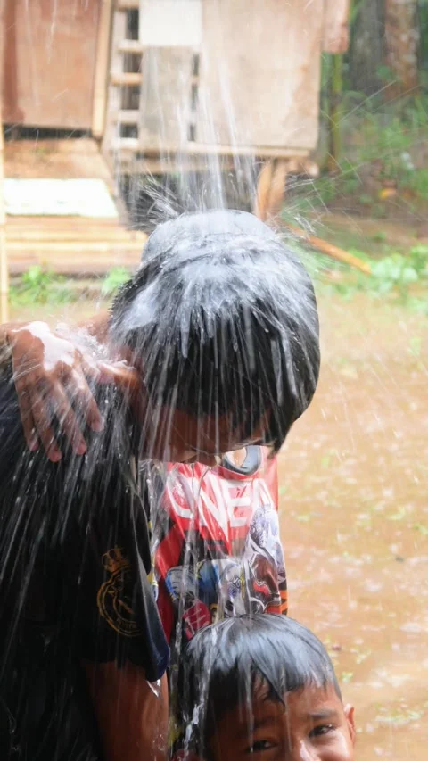 Boys are having fun playing in the rain in the yard. Stock Footage 308962988