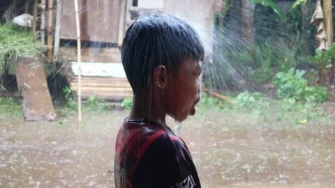 Boys are having fun playing in the rain in the yard. Stock Footage 308962991