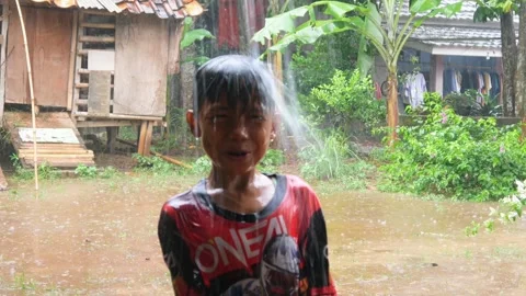Boys are having fun playing in the rain in the yard. Stock Footage 308962997