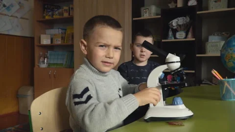 Boys are looking at something in a microscope Video stock 103982617