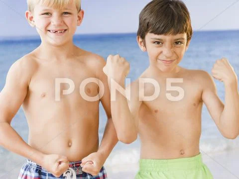 Boys on beach flexing biceps muscles Stock Photos