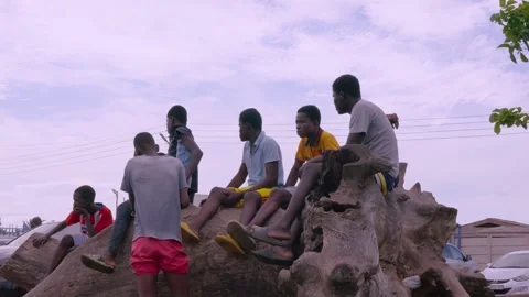 Boys chatting and playing while watching a soccer match in Ghana, West Africa 4k Vidéo 253556605