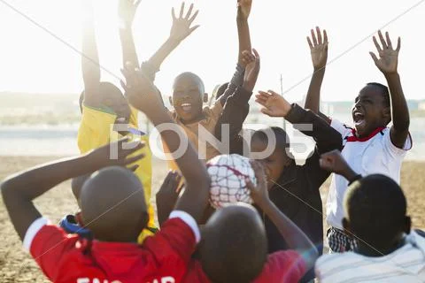 Boys cheering together in dirt field Stock Photos