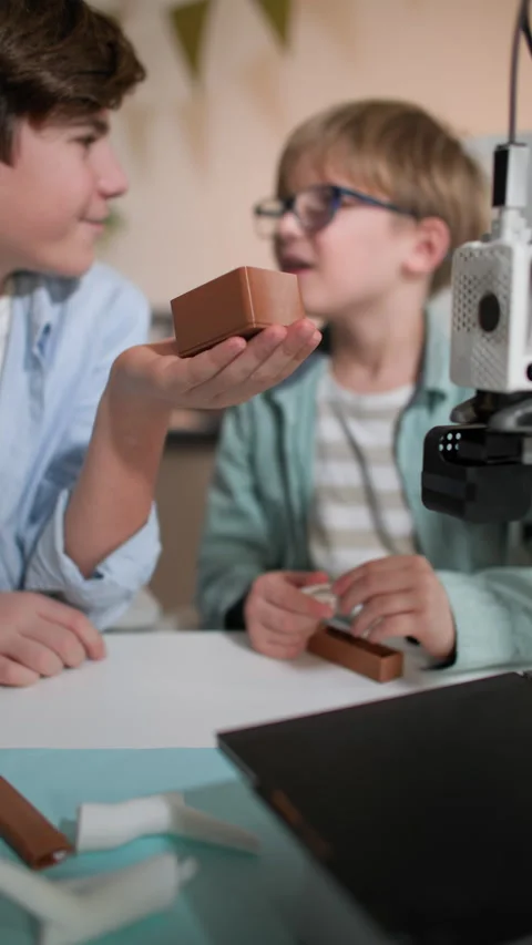 Boys examine and test a 3D printed part in their hands Stock Footage 335392584
