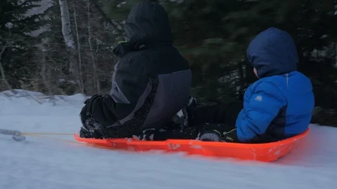 Boys getting pulled on a sled in the snow Stock Footage 92586279