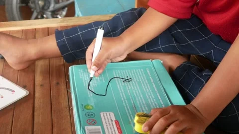 A boys hand scribbles on a green book cover using a black marker. Stock Footage 310519636