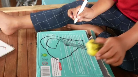 A boys hand scribbles on a green book cover using a black marker. Stock Footage 310519637