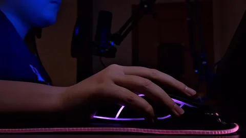 The boy's hand uses a computer mouse with neon lighting, bottom view, sitting in Video stock 274757813