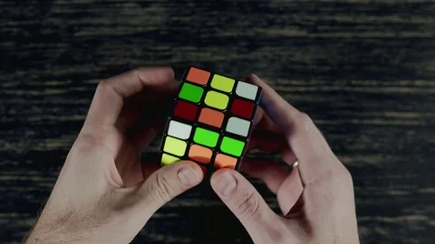 Boys hands solving puzzle cube at dark background. Top view in 4k, UHD, close up Vídeo Stock 82526005