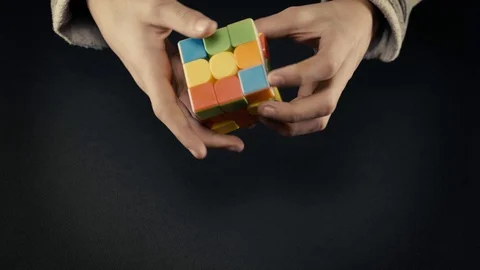 Boys hands solving Rubik's Cube 3x3x3 at dark background.Front view, 4k Stock Footage 125021968