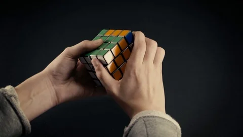 Boys hands solving Rubik's Cube 4x4x4 at dark background.Top view, 4k Stock Footage 125021989