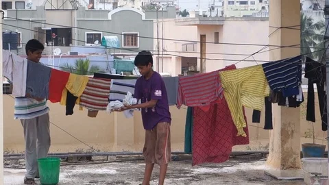 Boys hanging washed clothes for drying Stock Footage