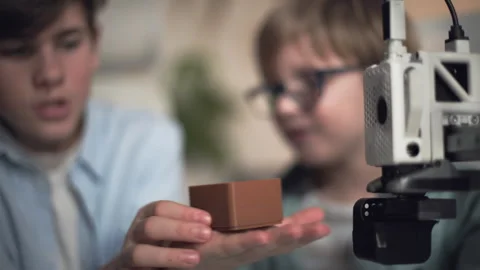 Boys hold a 3D printed box in which they place small parts Stock Footage 335376392