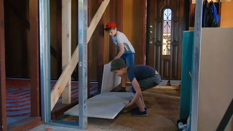 Boys lay sheets of insulation on the floor in the house Stock Footage 111672671