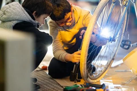 Boys learning bicycle repair using pump Foto stock
