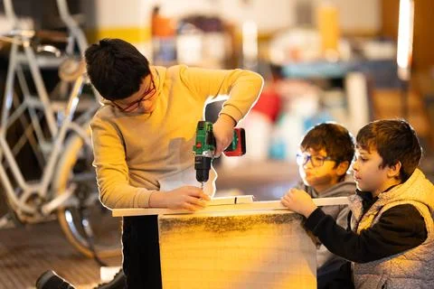 Boys learning woodworking using a drill in workshop Foto stock