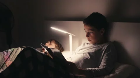 Boys lying in bed in dark and reading book. Vídeos de archivo 171250460