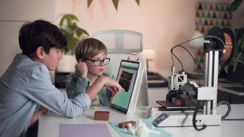 The boys makes adjustments to the 3D printer before starting a print Stock Footage 335379293