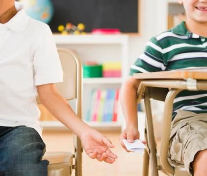 Boys passing note in classroom Stock Photos