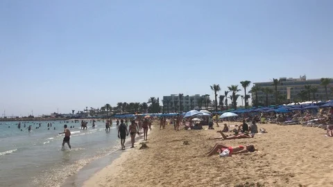 Boys play Beach Rackets vs a Girl lay down on the beach enjoying Tanning Stock Footage 91495157