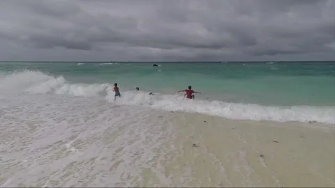Boys play with waves in the water on sandy beach, Malapascua island, Philippines 스톡 동영상 246574969