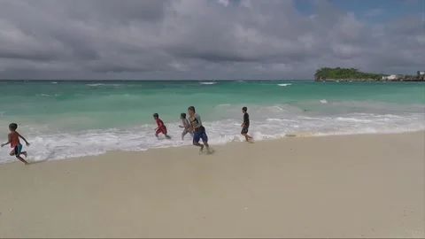 Boys play with waves in the water on sandy beach, Malapascua island, Philippines 스톡 동영상 246575902