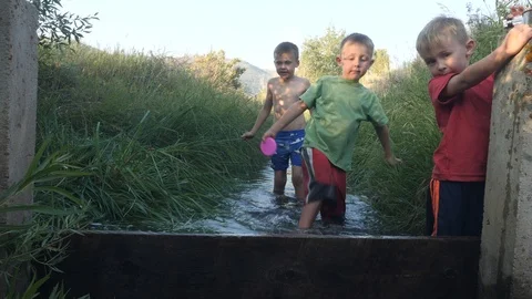 Boys playing in the ditch getting wet. Stock Footage 93446147