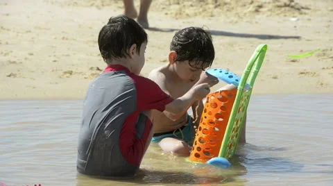 Boys playing with sand on the beach Stock Footage 50555230