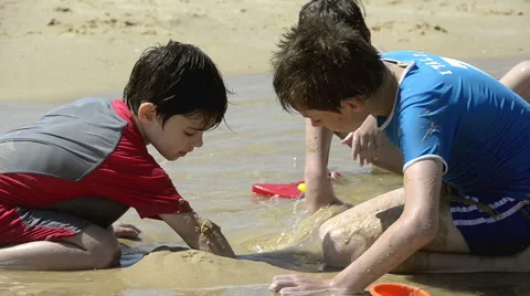 Boys playing with sand on the beach Stock Footage 50555266