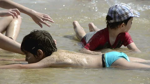 Boys playing with sand on the beach Stock Footage 50556640