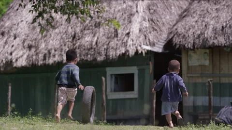 Boys playing with tire outside a hut in village, Guatemala Stock Footage 63053653