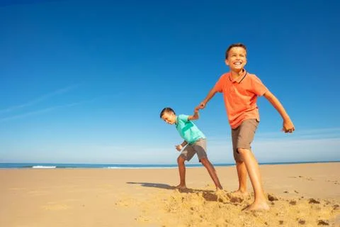 Boys pull each other on the beach towards sea Stock Photos
