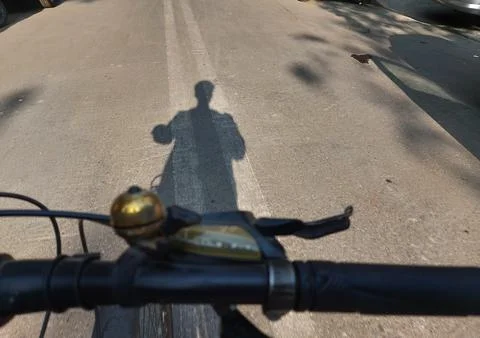 Boy's shadow on road while riding gear cycle at fast speed, evening Stock Photos