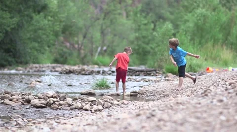 Boys throwing rocks in river Stock Footage 43386507