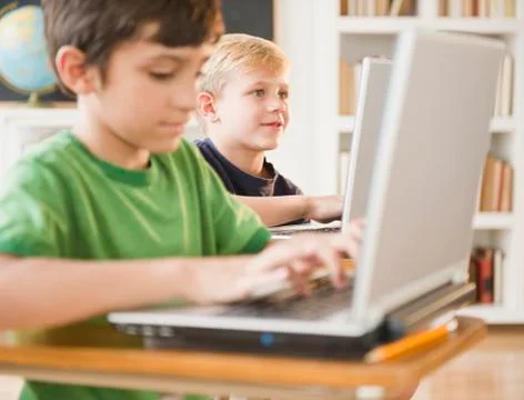 Boys using laptops in classroom Foto stock