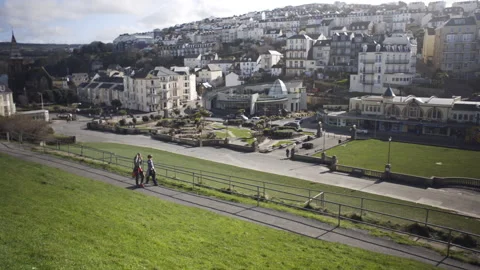Boys walking along path in grassy park in Ilfracombe Stock Footage 136876074