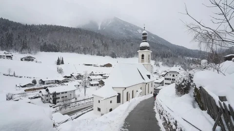 Boys walking up path in winter next to Bavarian church Stock Footage 121754375
