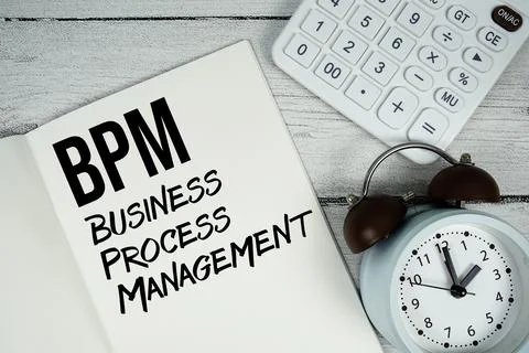 BPM Business Process Management text on paper notebook page with alarm cloc.. Stock Photos