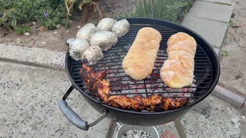Braai Grill with Grilled Chicken, Bread Rolls, and Foil-Wrapped Potatoes Video stock 346839296