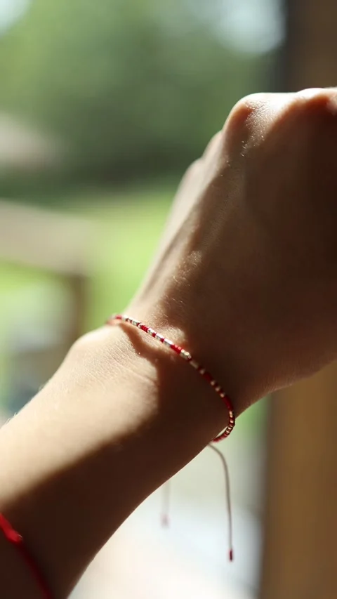 Bracelet made of red thread on the wrist of a woman's in the rays of the sun 스톡 동영상 246549310