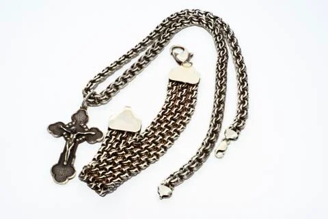 Bracelets, chains and crosses of silver on a white background Stock Photos