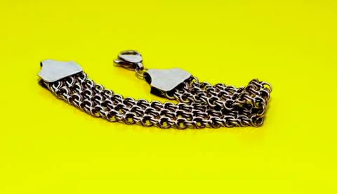 Bracelets, chains and crosses of silver on a yellow background Stock Photos