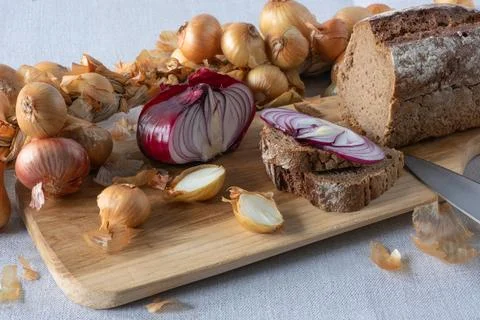 A braid of bulbs around an ash cutting board. Golden and red onions whole a.. 写真素材