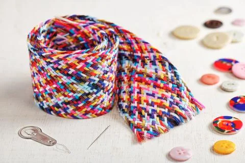 A braid of multi colored sewing threads, needle, needle threader, buttons lyi Stock-Fotos