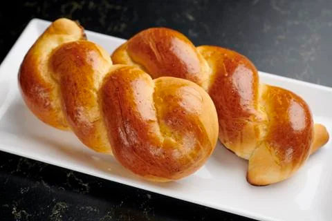 Braided brioches on a white rectangular plate Foto stock