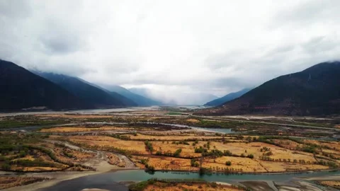 Braided river and golden fields between cloudy mountain slopes in Tibet Vidéo 345884109
