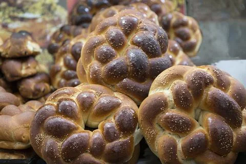 Braided rolls of fresh white bread with sesame seeds and grains close-up Stock Photos